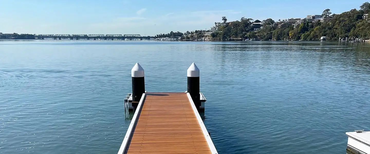 A jetty running straight out to two capped mooring piles on a clear day