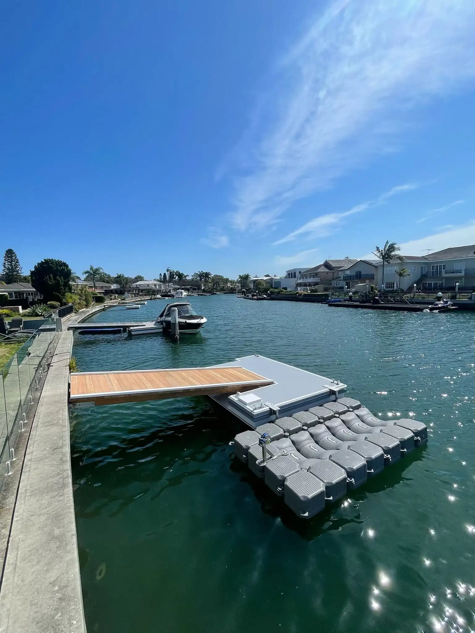 White pontoon and grey modular floating dock sitting side by side off a hardwood gangway, showing the two options together