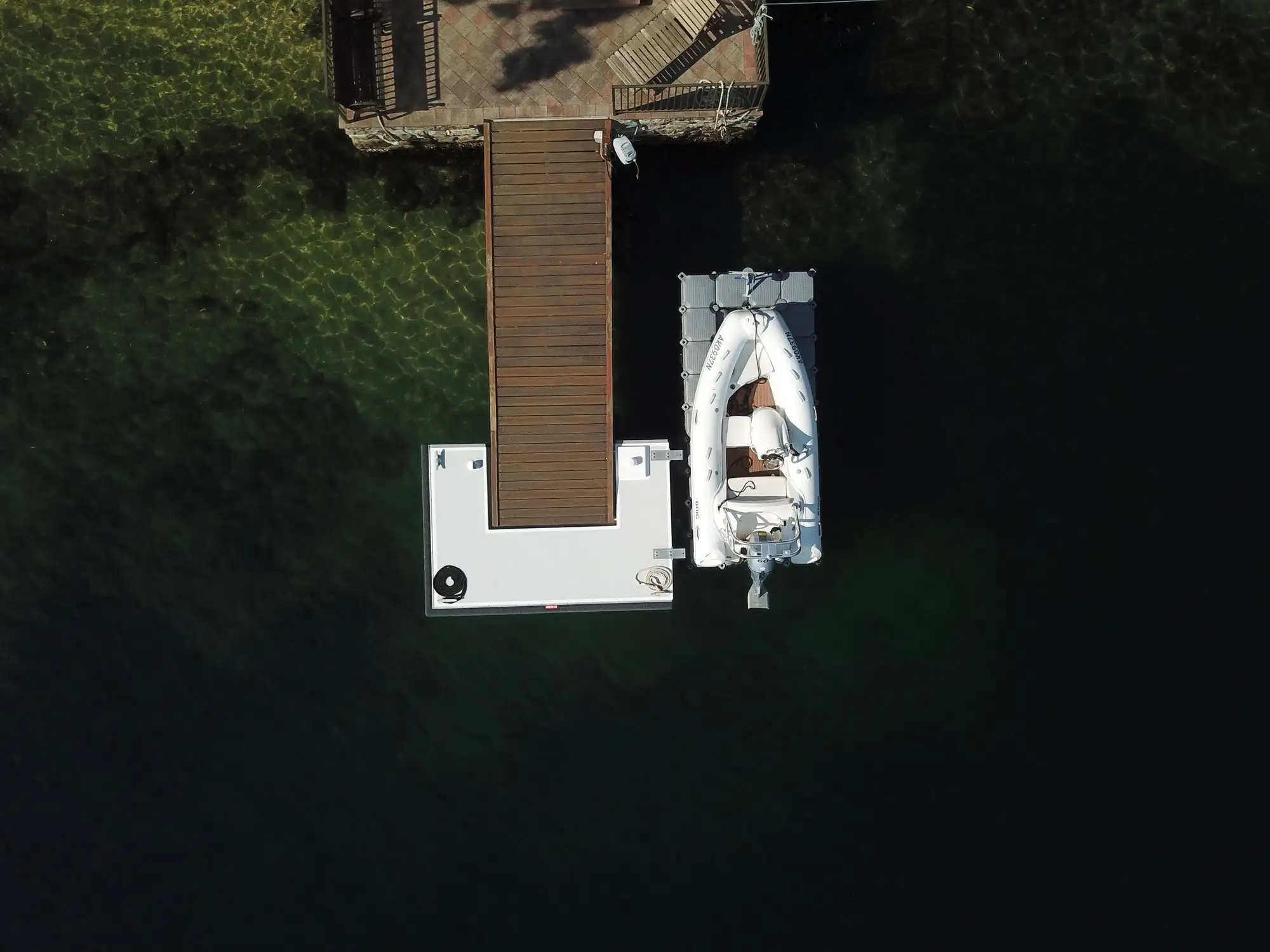 Aerial view straight down onto a Kingtide Marine jetty, pontoon and floating dock with a RIB berthed on it