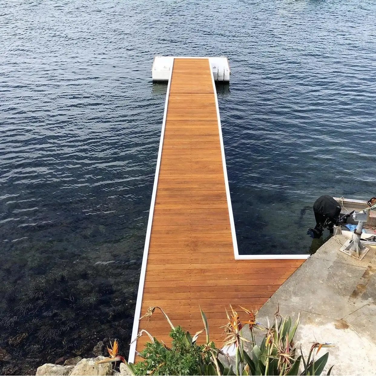 Hardwood jetty deck and balustrade running out from a landscaped waterfront