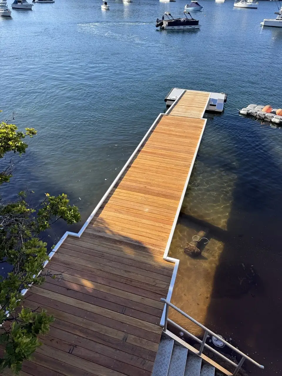 Aerial view of a hardwood jetty running out to a pontoon with boats moored beyond