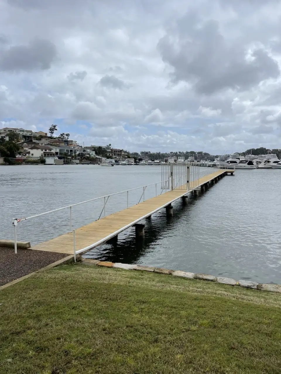 A jetty running out from a waterfront lawn on an overcast day