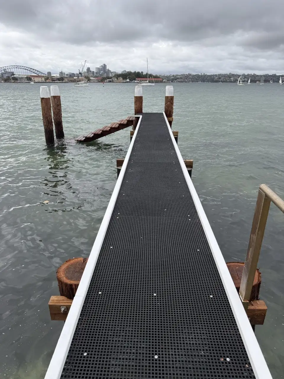 Open-mesh jetty decking running out to capped timber piles