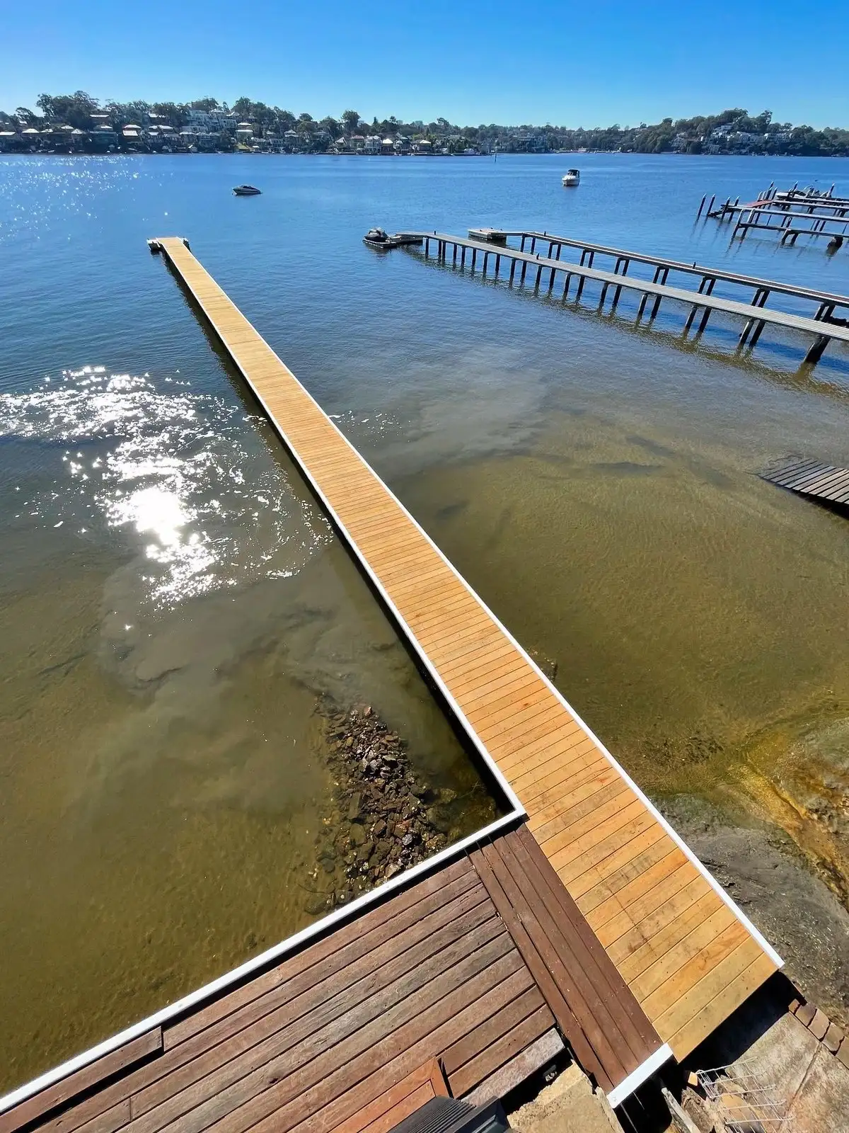 A jetty reaching out across still water towards moored boats on a clear morning