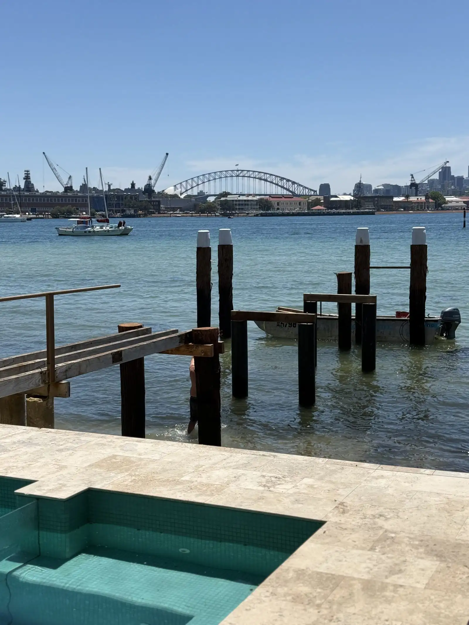 Black-coated steel piles standing in the water off a waterfront property, protected against corrosion below the waterline