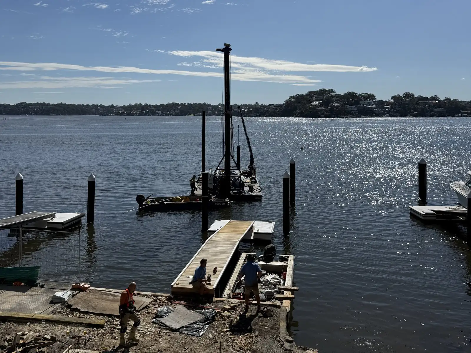 The drill rig set up on Kingtide Marine’s barge driving piles off a waterfront, with the crew working from the shore
