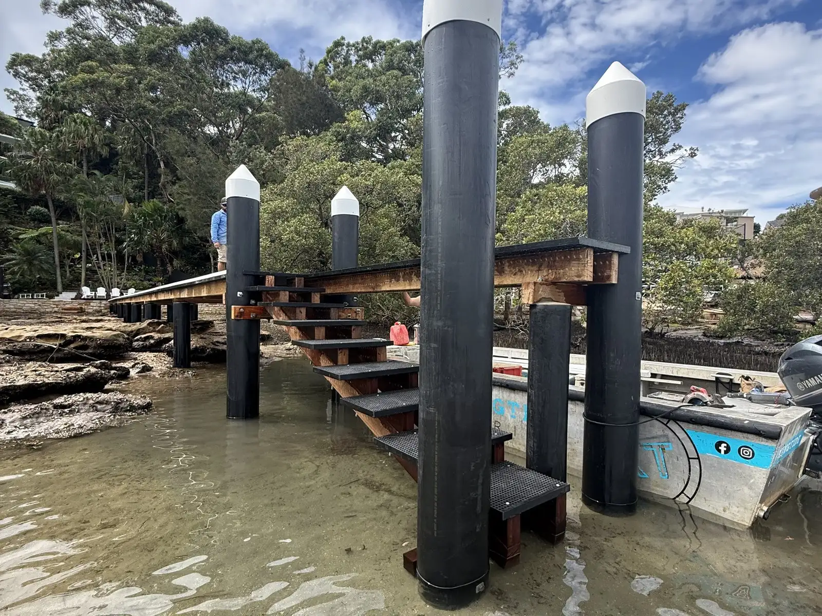Black HDPE-sleeved piles with white caps carrying a jetty and its stair landing