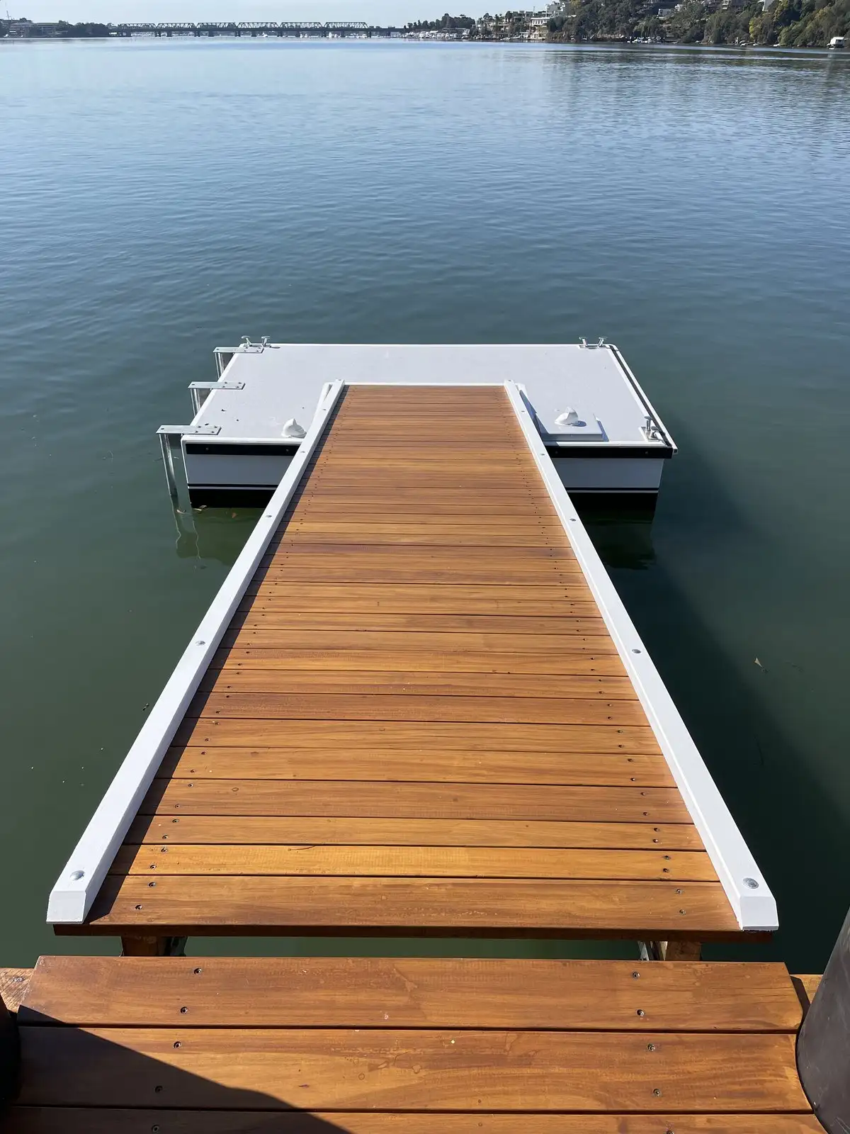 Freshly oiled hardwood gangway running down to a pontoon on open water