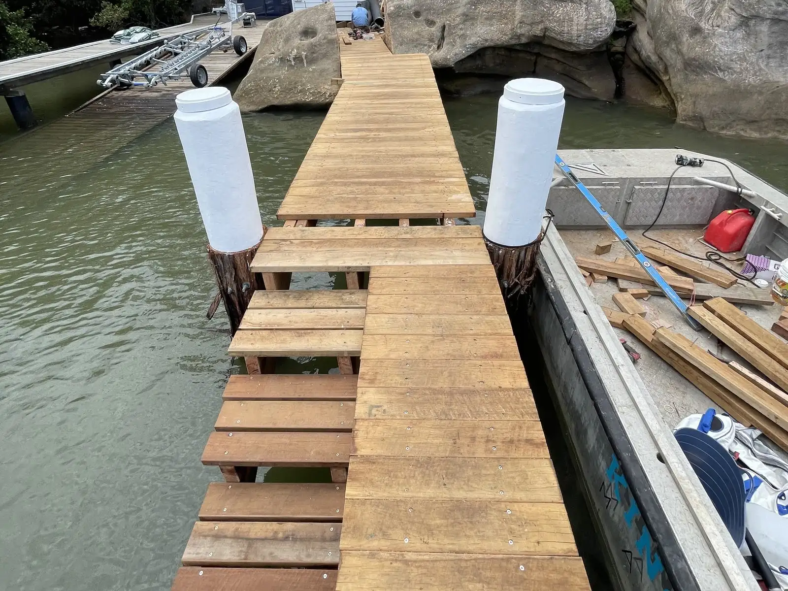 A jetty part way through a rebuild, with new piles driven and fresh hardwood decking going down over the old frame
