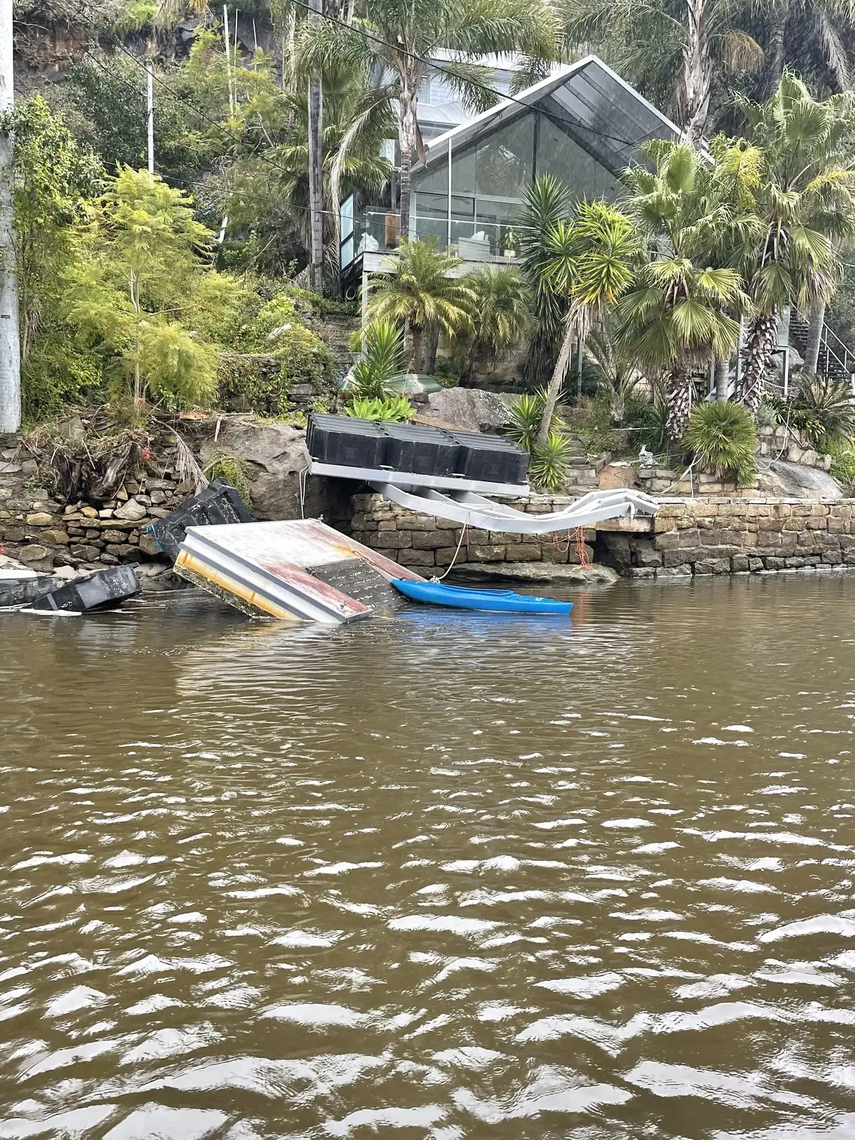 A part-sunken boat alongside a failing jetty awaiting salvage