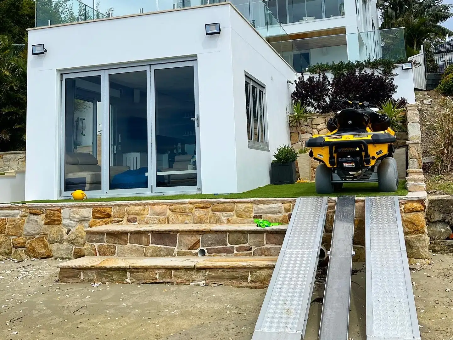 Coursed sandstone seawall with cut stone steps and a ramp up to the lawn and boat shed above