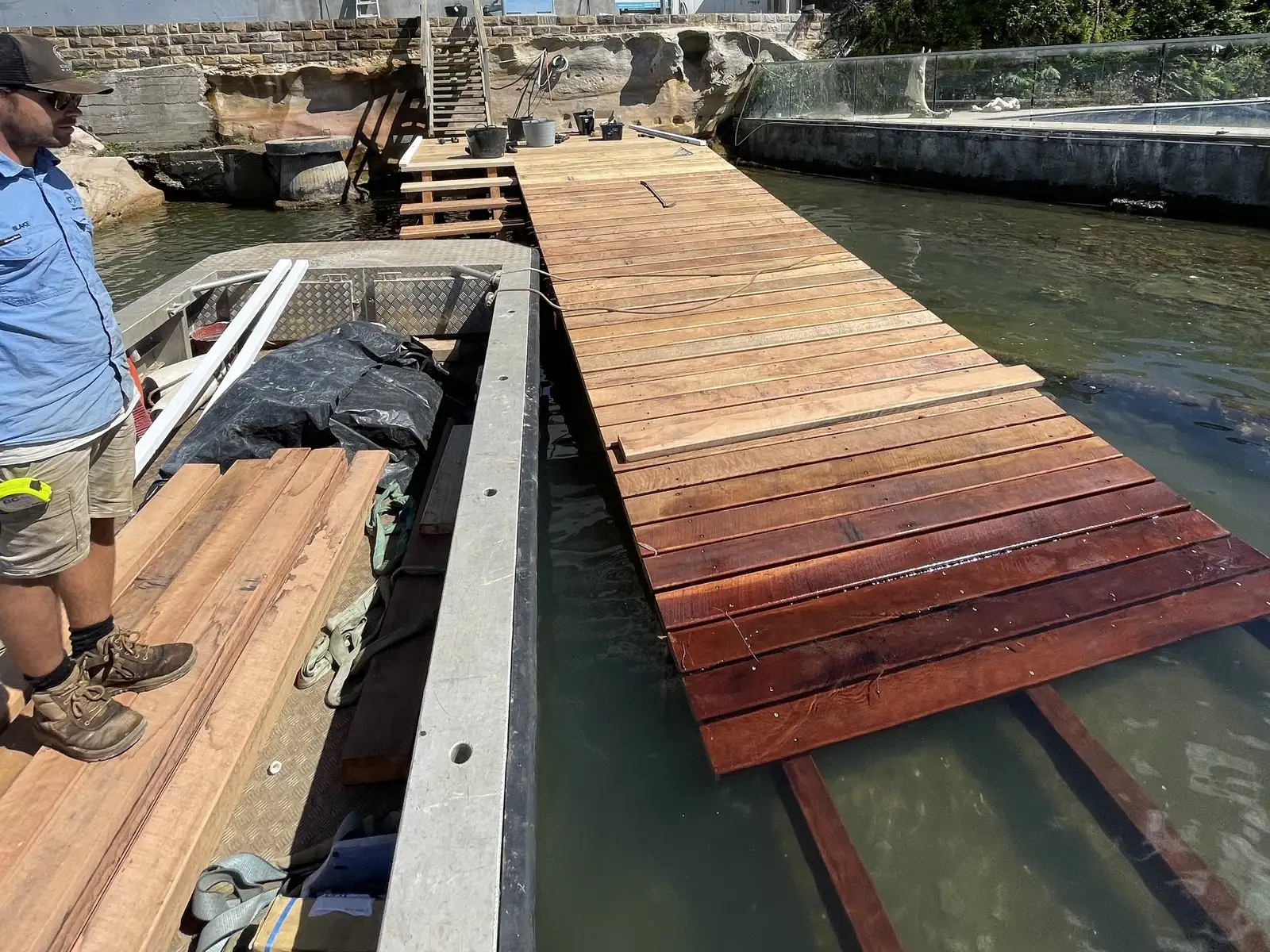 Kingtide Marine crew laying new hardwood boards on a skid ramp from the work punt alongside