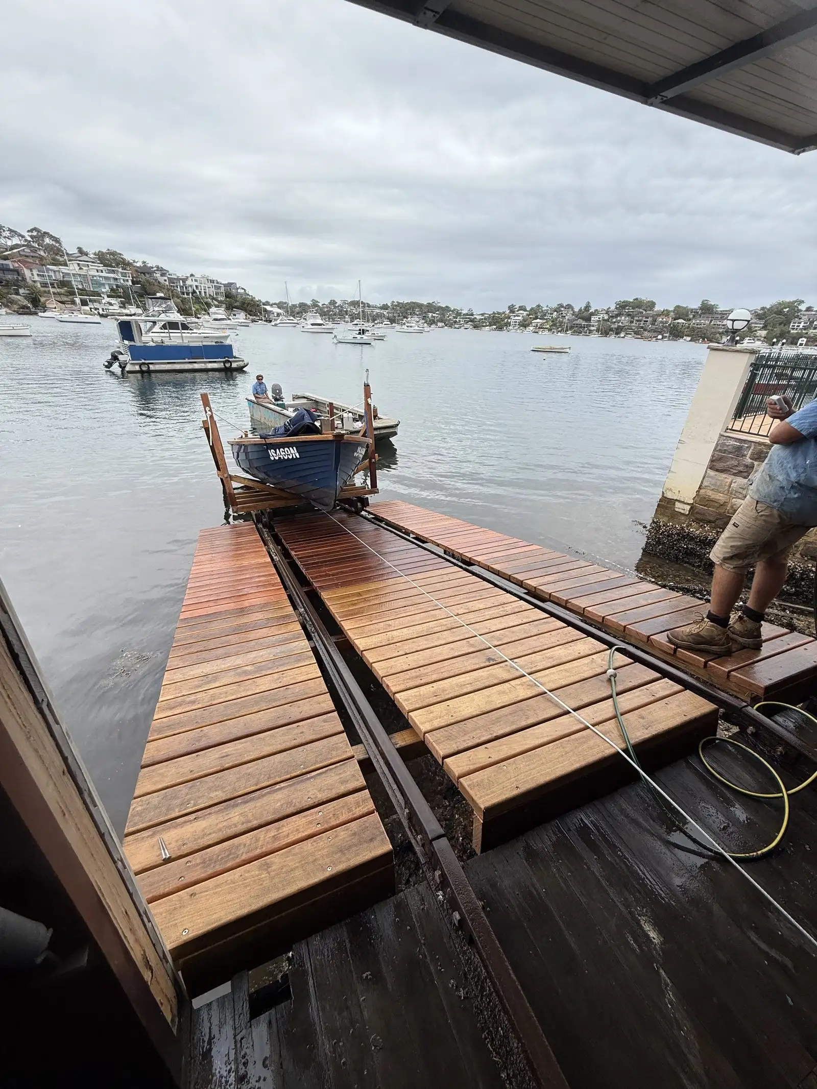 Slipway rails running alongside a hardwood jetty deck, with a boat moored off the end of the jetty