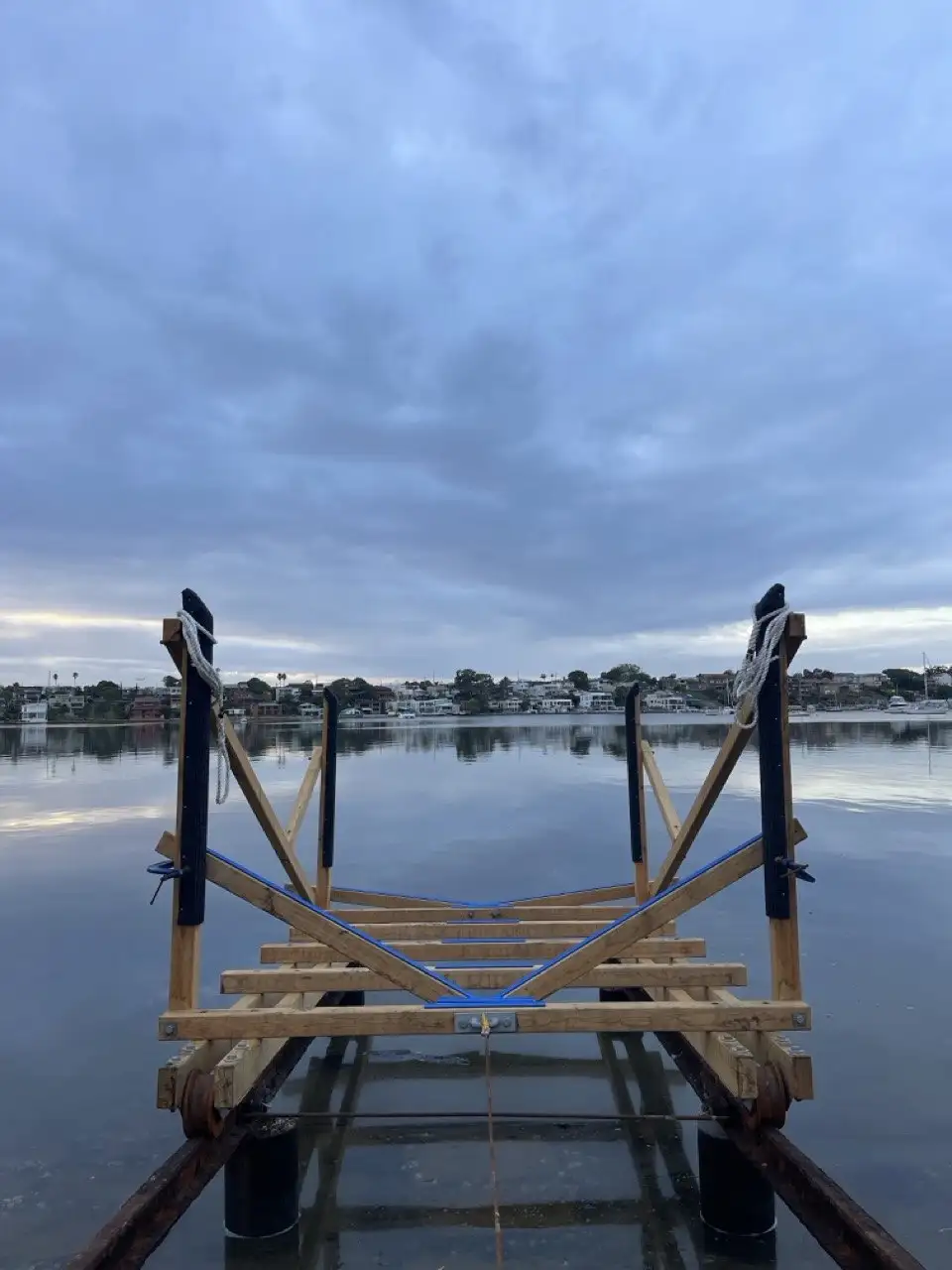 Slipway rails and cradle running into still water at dusk