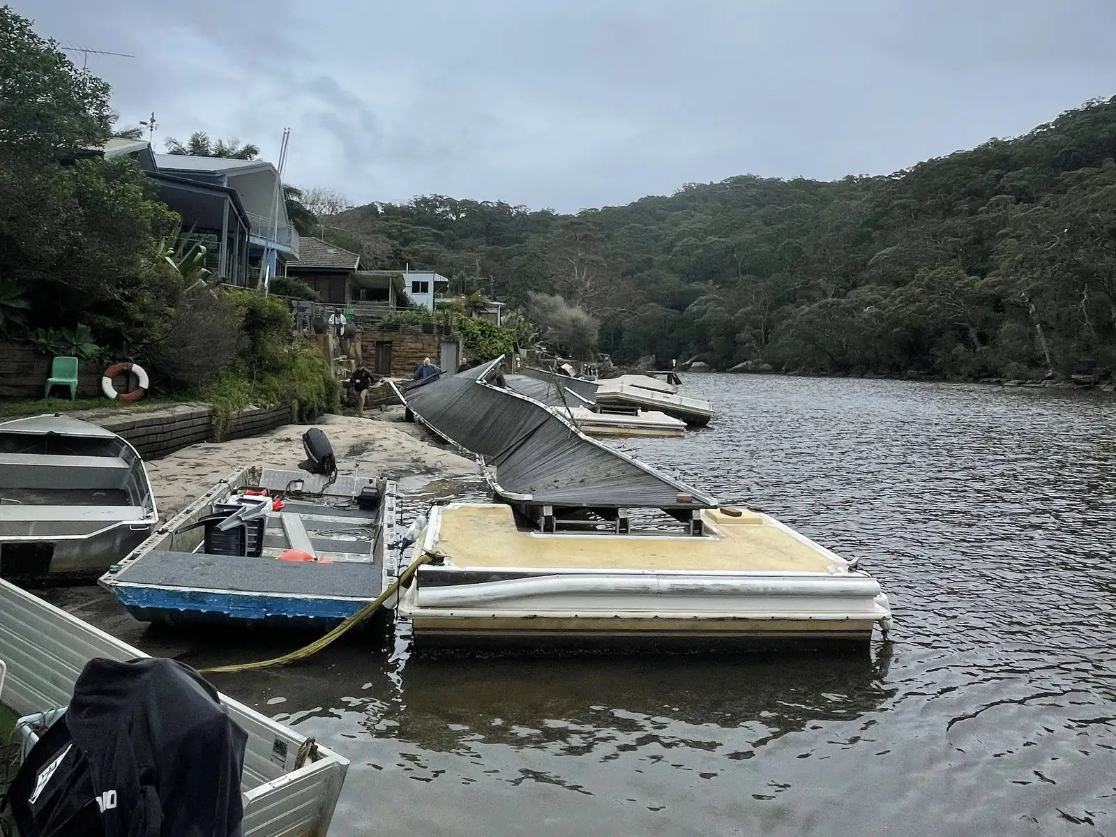 Crew alongside displaced pontoons in work boats, recording the damage after a storm