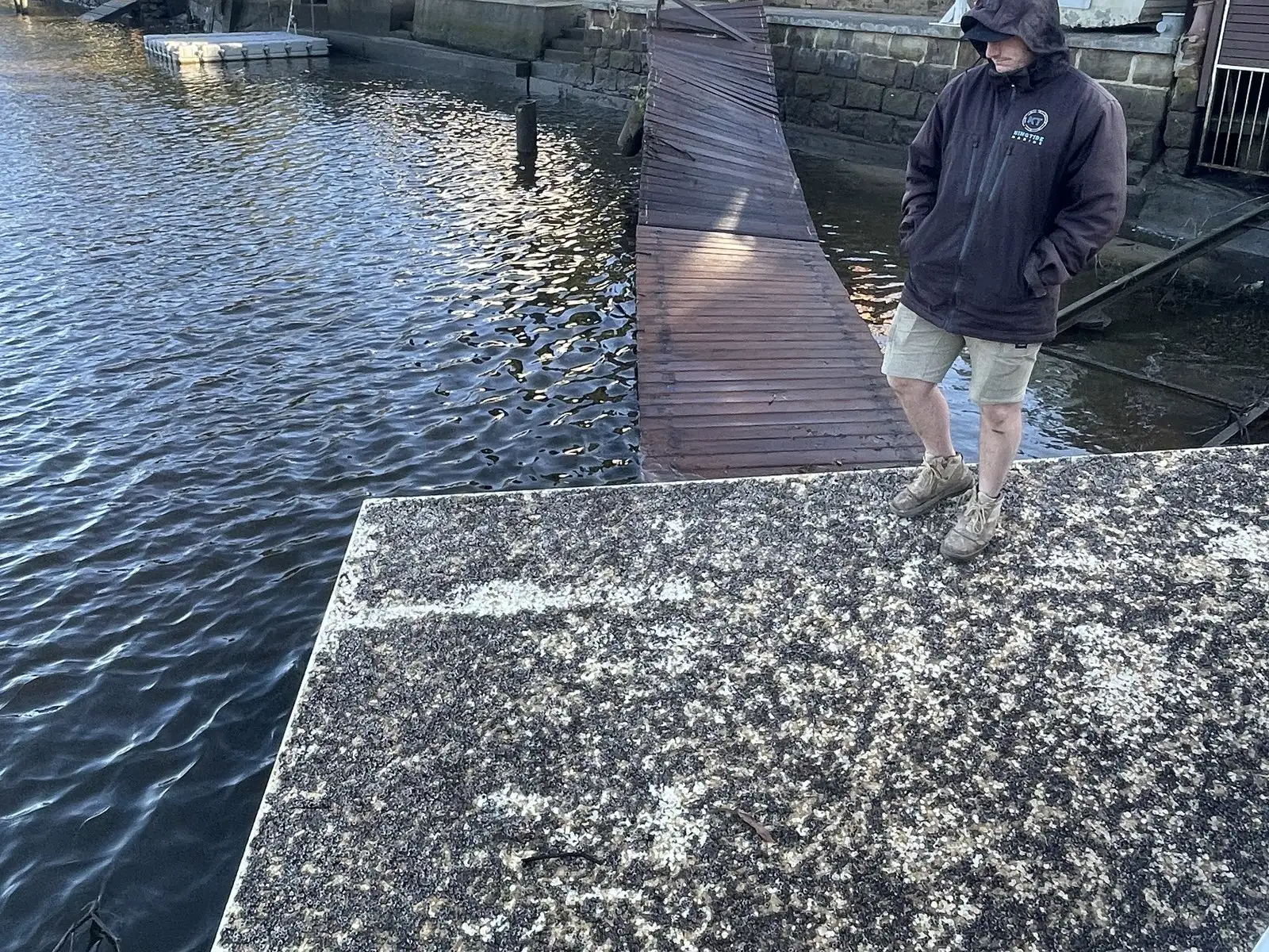 Kingtide Marine crew walking a storm-hit jetty in the wet to check what is safe to stand on