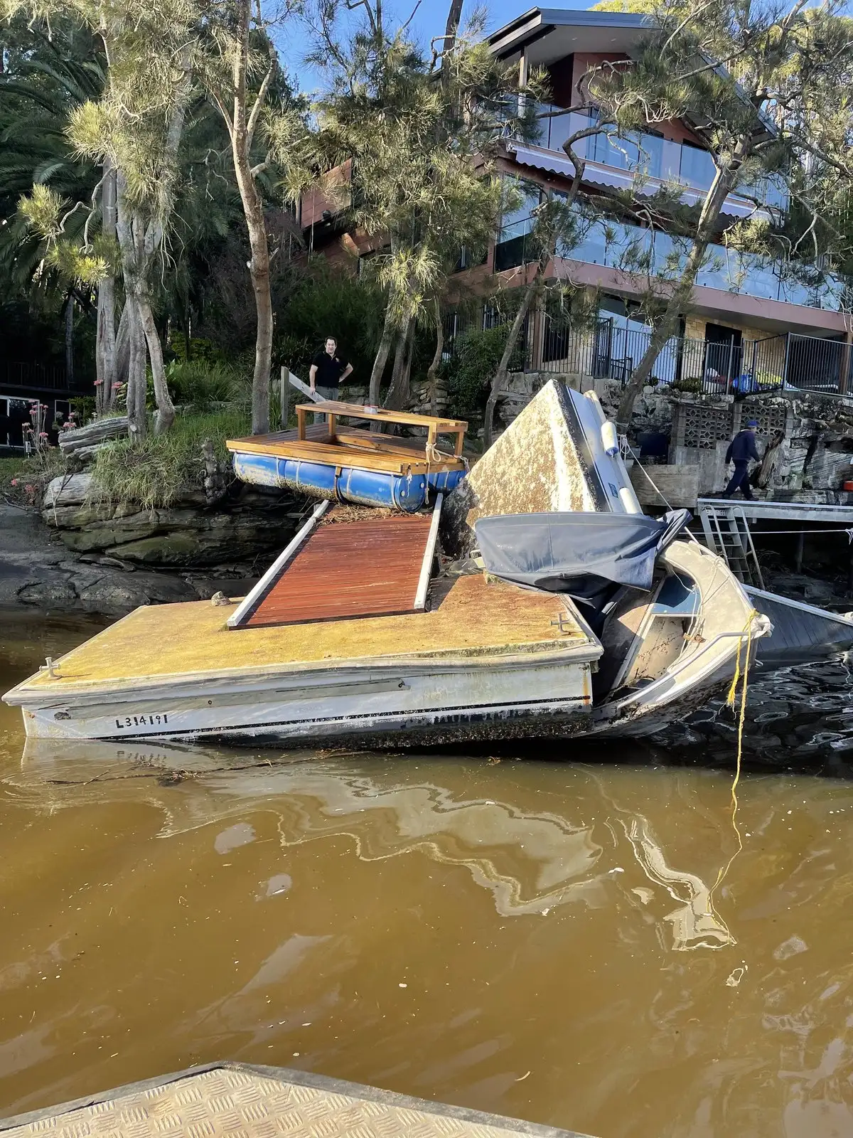 A sunken boat and storm debris piled against a damaged jetty