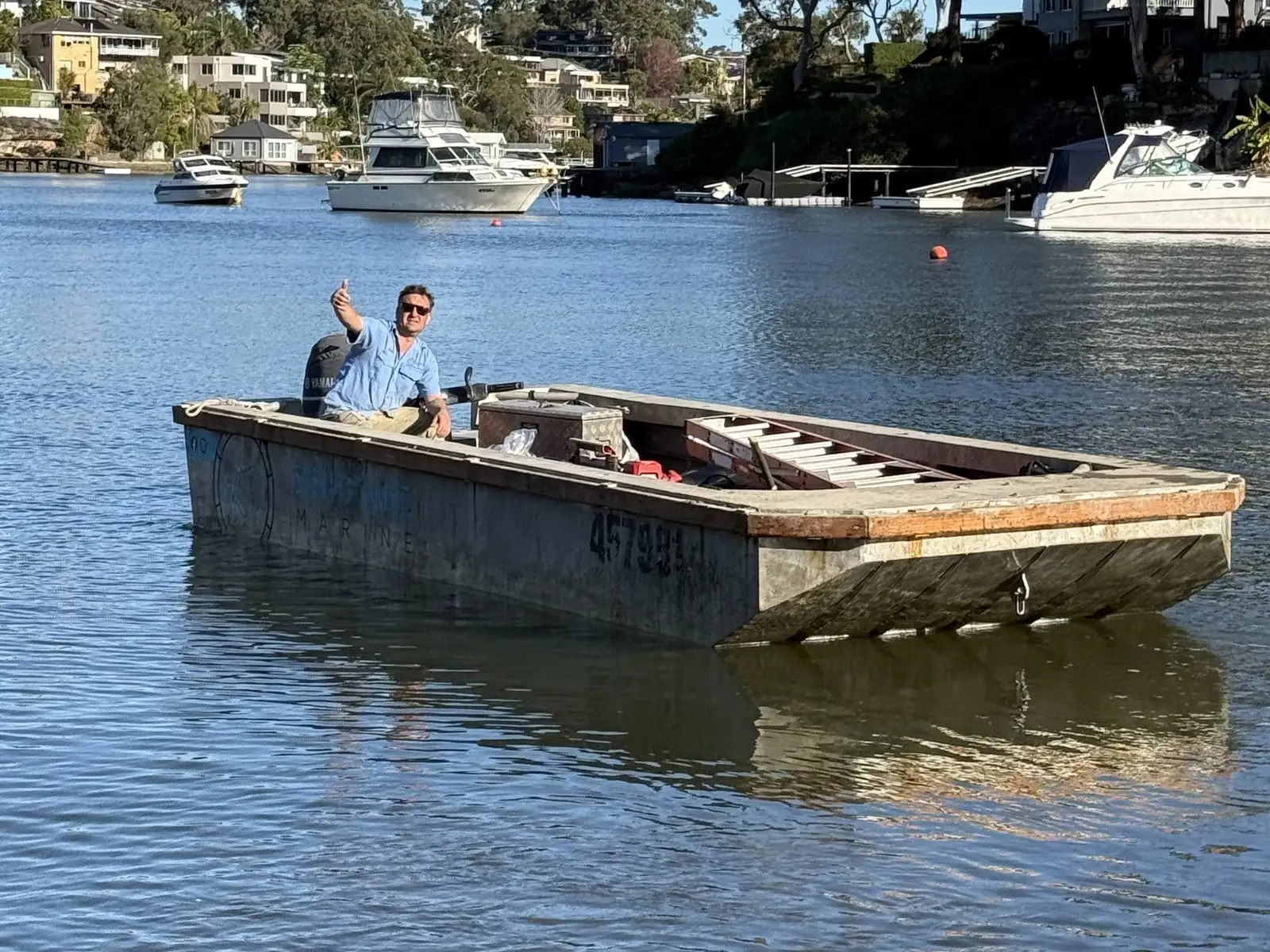 The Kingtide Marine punt under way with one skipper at the outboard and the deck loaded with gear