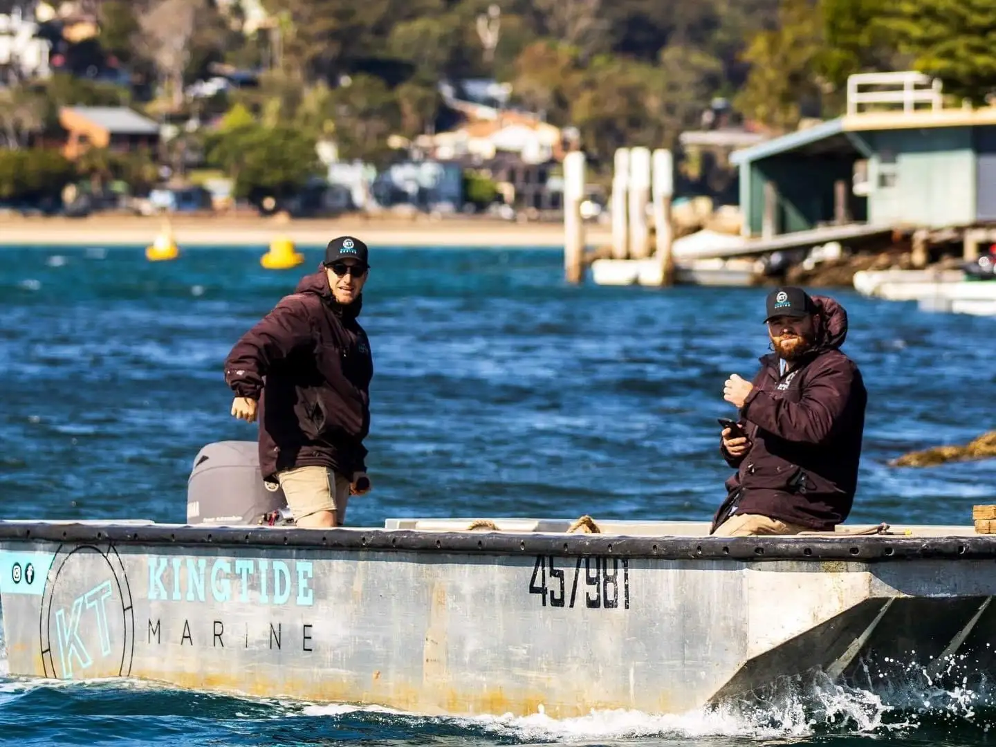 The Kingtide Marine work punt under way across open water with two crew aboard
